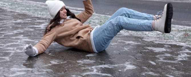 Young woman fallen on slippery icy pavement outdoors